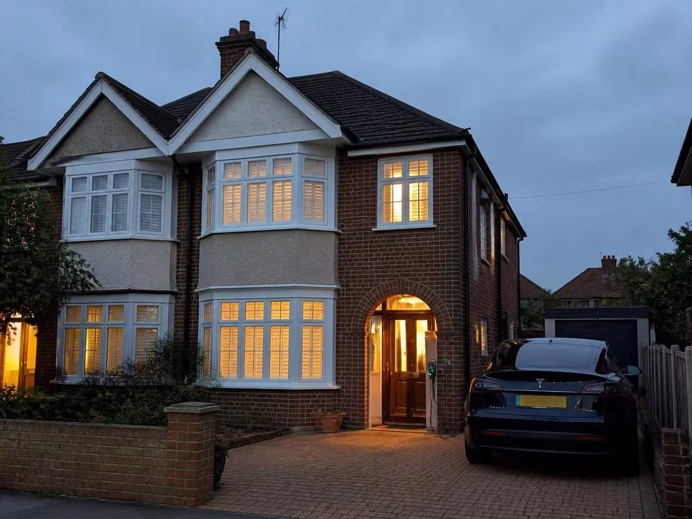 Kent home at dusk with a wall mounted EV charge point on the driveway